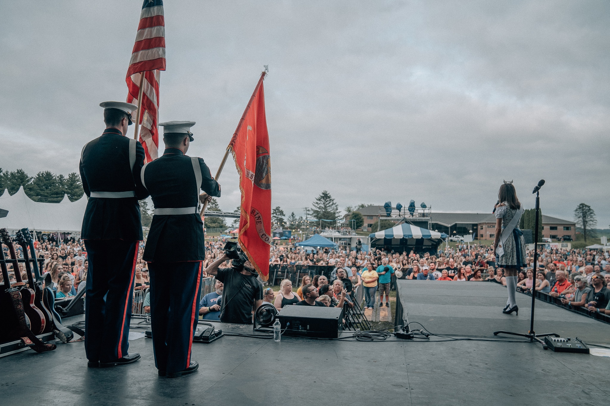 Military men on stage holding United States flags in front of a crowd of country music fans